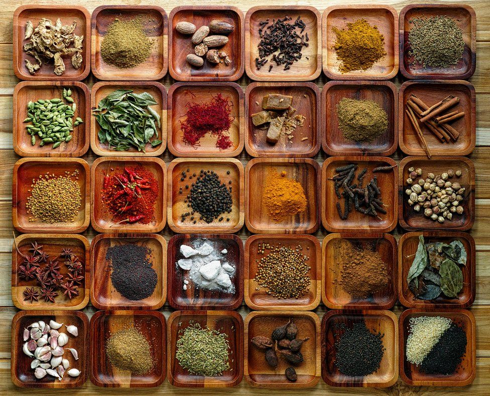 Common Indian herbs and spice ingredients on wooden trays.