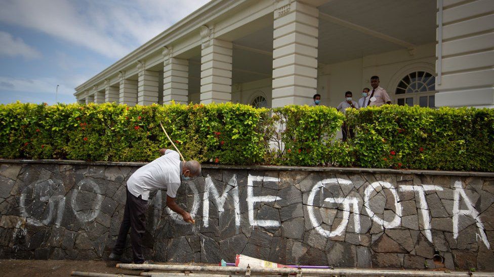 A staff member washes graffiti left behind by protestors from a hotels compound wall near a protest site on July 18, 2022 in Colombo, Sri Lanka.