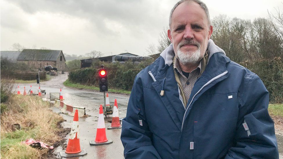 Ian Chandler standing in from of traffic lights and pylons at Trebella Farm