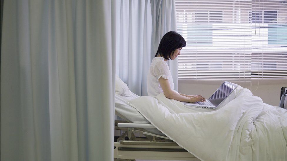 Woman using laptop in hospital bed