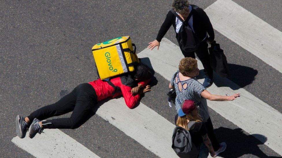 A Glovo's delivery boy lies over the 9 de Julio avenue as pedestrians try to help after a car crashed him in the intersection with the Av. de Mayo Avenue, Buenos Aires, Argentina,Sunday, November.25,2018.