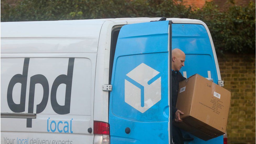 A DPD delivery worker next to his van