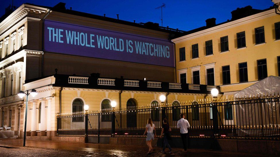 A sentence reading The Whole World is Watching is projected on the presidential palace on the eve of a summit between US President Donald Trump and Russian President Vladimir Putin in Helsinki on July 15, 2018