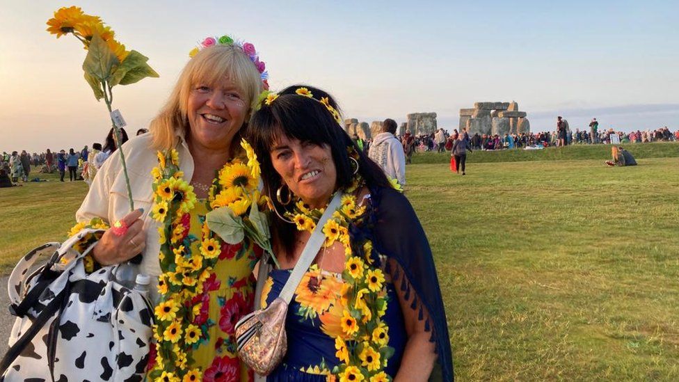 Janet Burns and Gill Richardson wearing sunflowers with the stone circle in the background