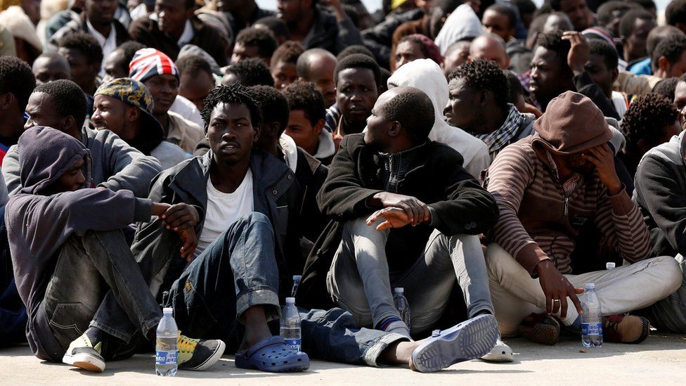 Migrants rest after disembarking from the Italian Navy vessel Grecale in the Sicilian harbour of Augusta