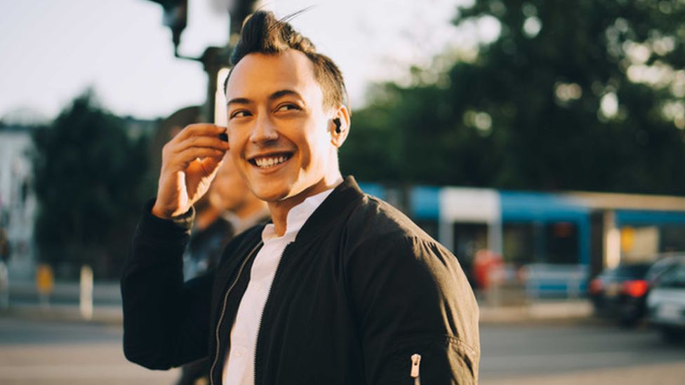 A young man wearing in-ear headphones