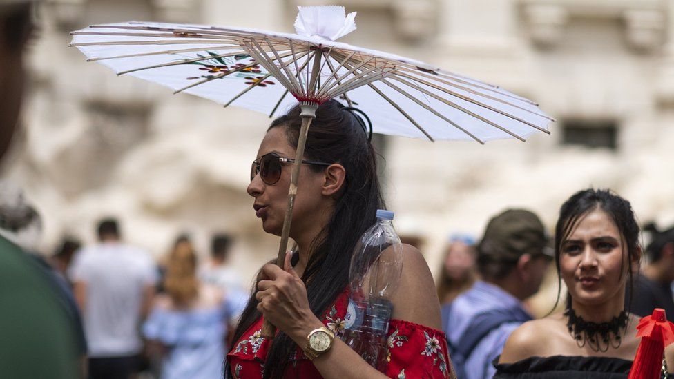 A tourist holds a sun umbrella in Rome, Italy.