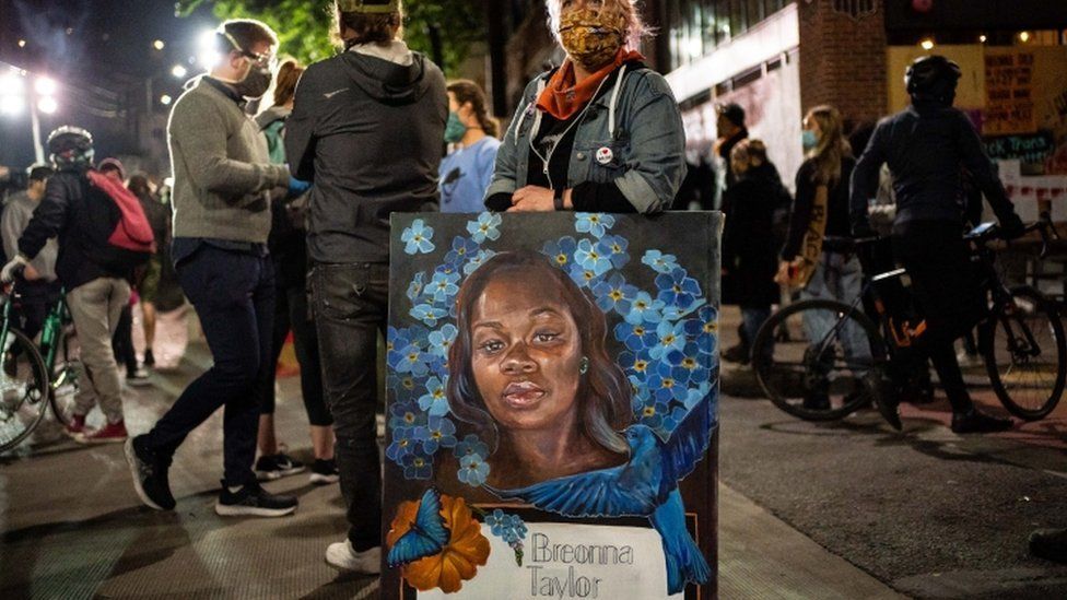 A demonstrator holds a painting of Breonna Taylor during a protest near the Seattle Police Departments East Precinct