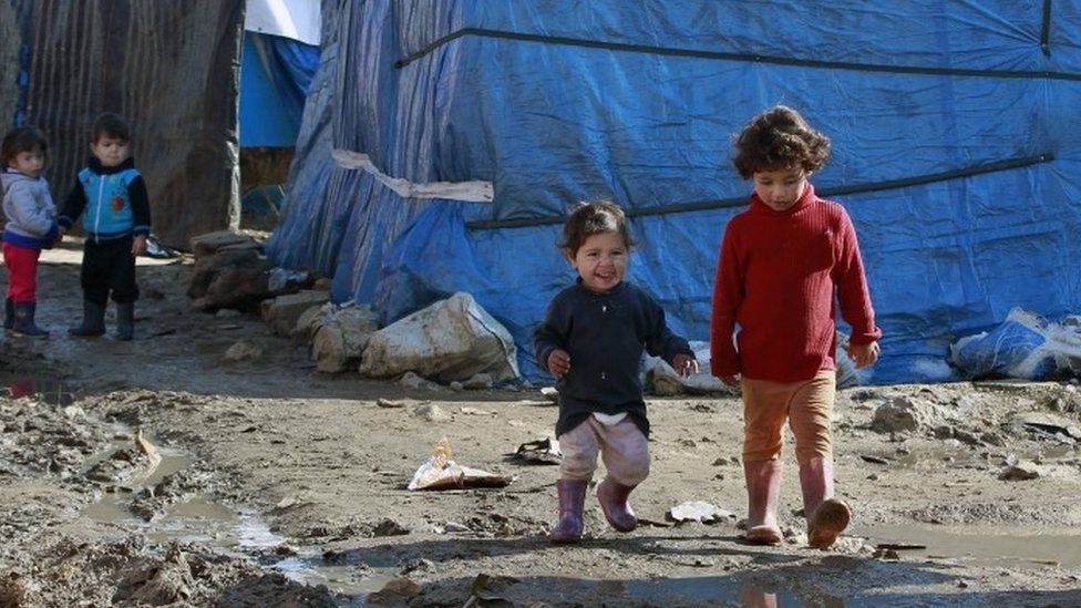 Syrian refugee children walk outside their family tents at a Syrian refugee camp, in the eastern town of Kab Elias, Lebanon