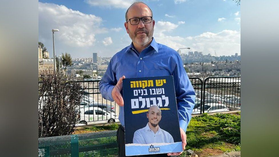 Zvika Mor holds up a poster with his son's face on it