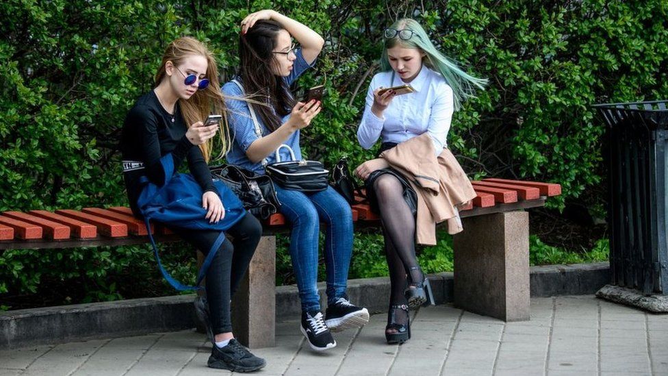 Молодые люди смотрят в свои телефоны