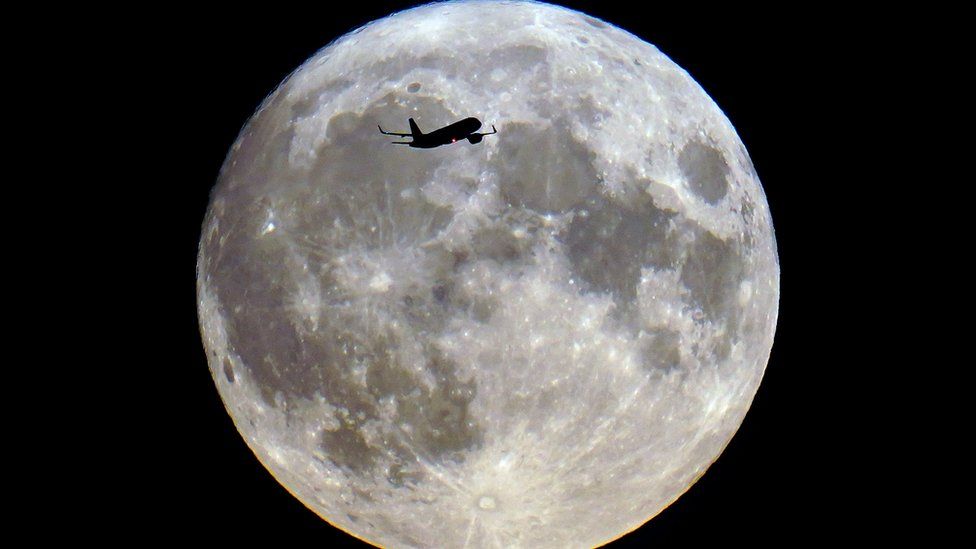 Plane flying past supermoon
