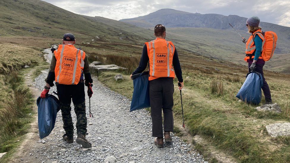 Litter pickers on a path with rubbish bags