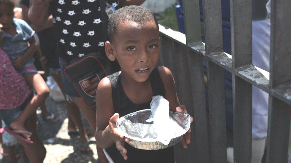 Boy receiving food handout in Rio de Janeiro, March 2021