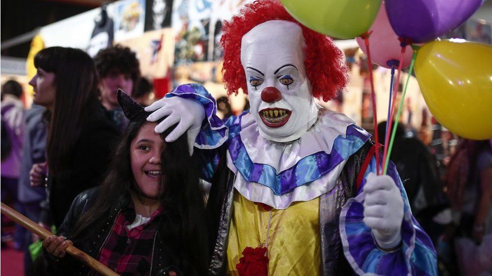 A man dressed as the clown from Stephen King's novel 'It' plays with a girl at the Anime Friends, a gaming and comic event in Buenos Aires, Argentina, on 24 July, 2016.