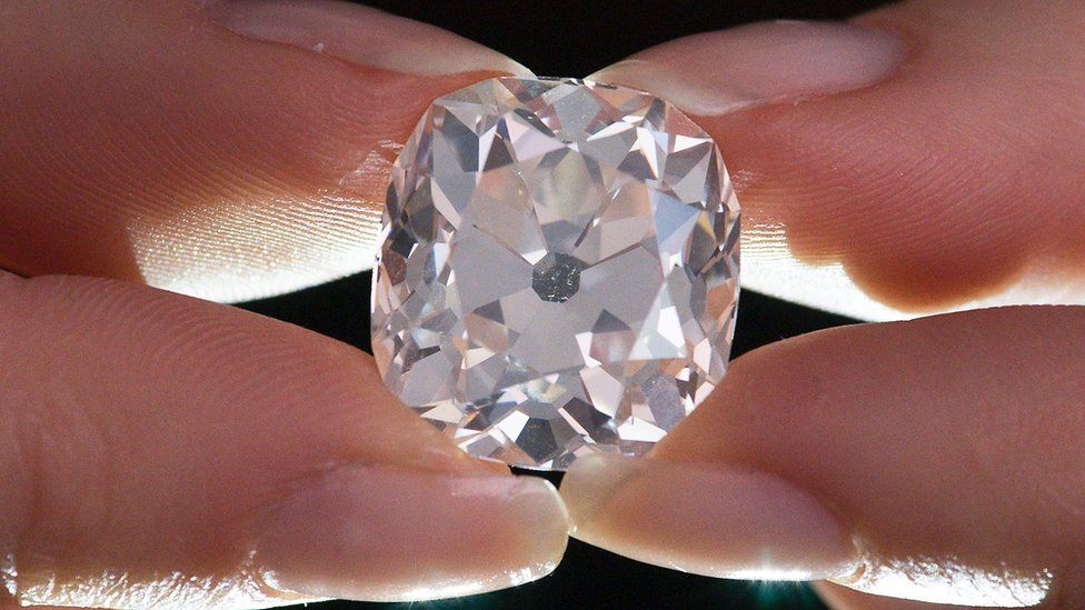 A member of Sotheby"s staff poses holding a 26.27 carat, cushion-shaped, white diamond