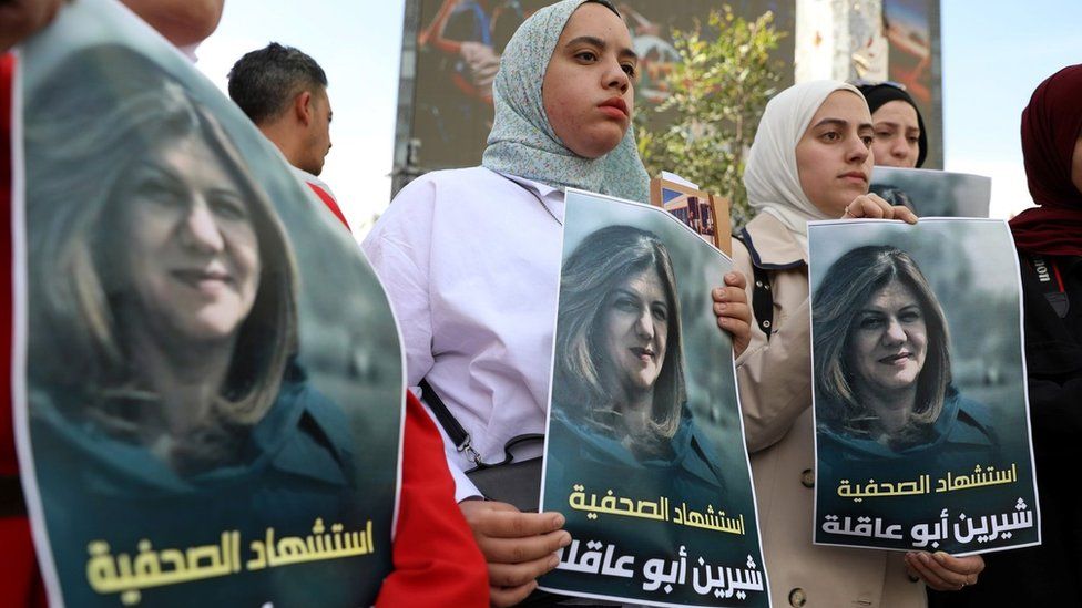 Palestinian journalists hold up posters showing Sherine Abu Aqla, who was killed during an Israeli raid in the occupied West Bank city of Jenin (11 May 2022)