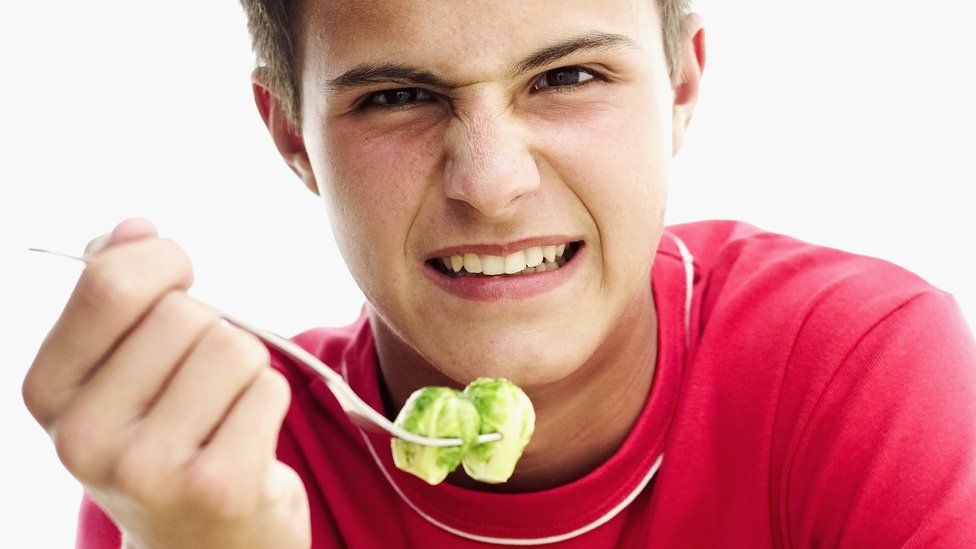 Teenage boy reluctantly eating veg
