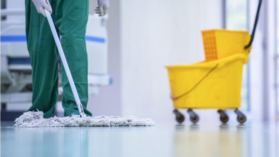 Больничный уборщик моет полы