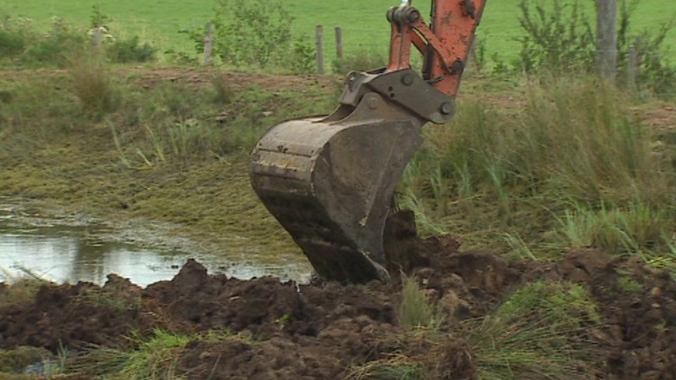 A digger filling in the pond on Mr Meakin's land