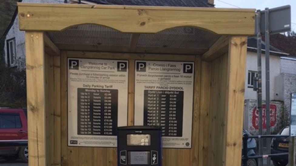 Parking meter and signs in a covered shelter in Llangrannog