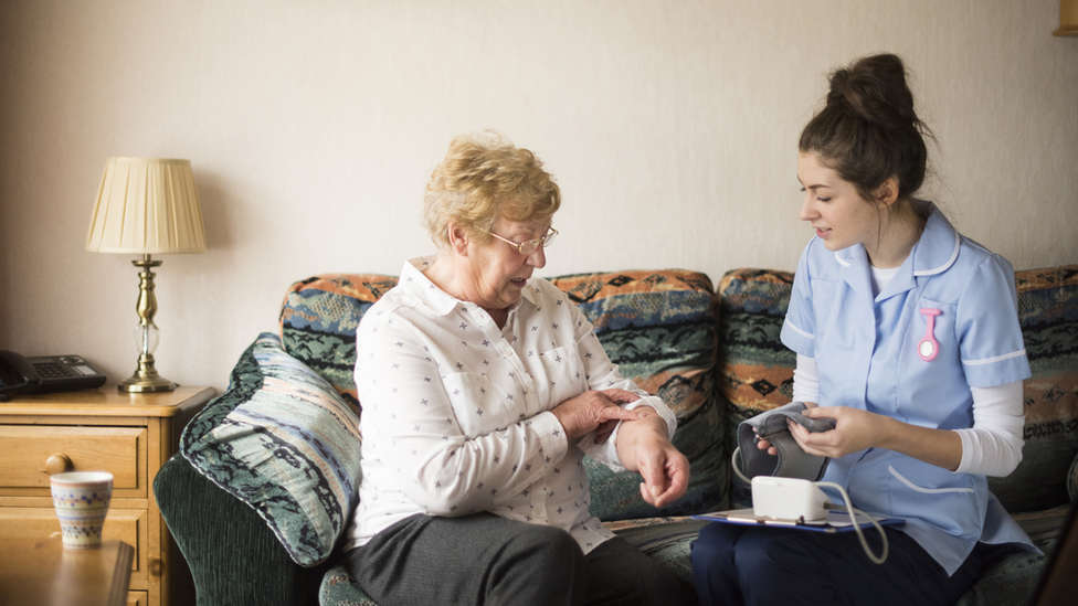 A social care worker helping an older woman with a health check