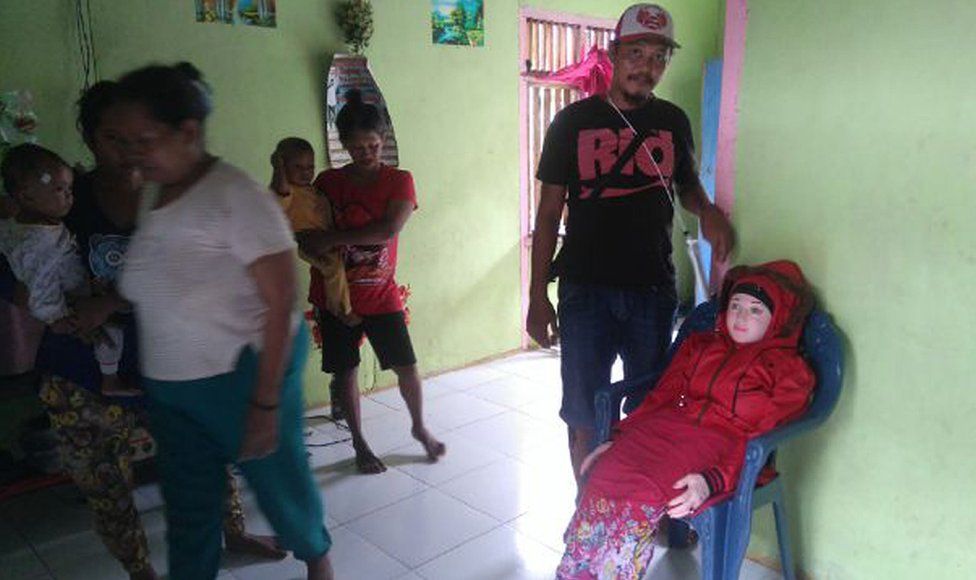 This recent undated handout picture released by Indonesian police and made available on 3 May 2016 shows an Indonesian man standing next to a sex doll (R-on chair) at a home in Banggai in Sulawesi.