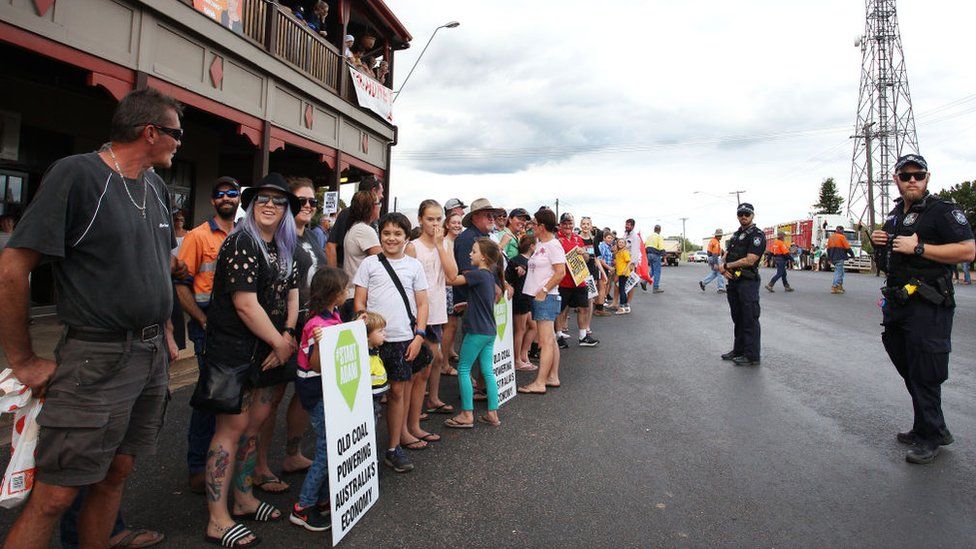 Demonstrators hold placards saying "start Adani - Queensland coal powering Australia's economy"