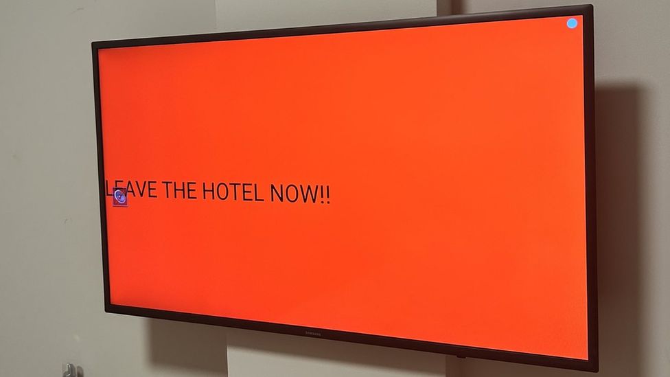 Alert on a TV screen reading: andquot;LEAVE THE HOTEL NOW!"