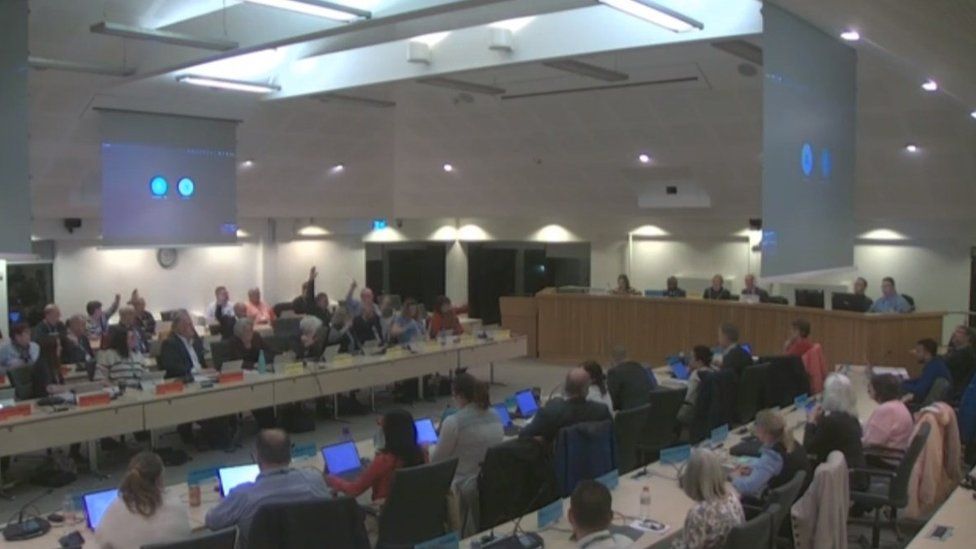 A photo of the council chamber and the meeting in session.