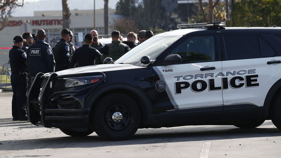 Police officers gather as investigators go through a white van which police reported was connected with a mass shooting at a dance studio in Monterey Park, California