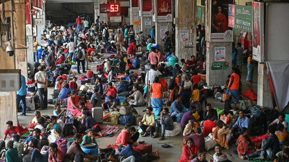 Stranded passengers gather at a railway station while waiting for their trains after heavy rains in Chennai on December 6, 2023.