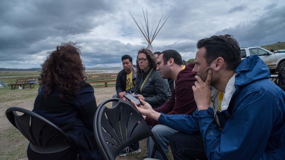 A group from Amnesty International crowd around LaDonna Brave Bull, recording an interview.