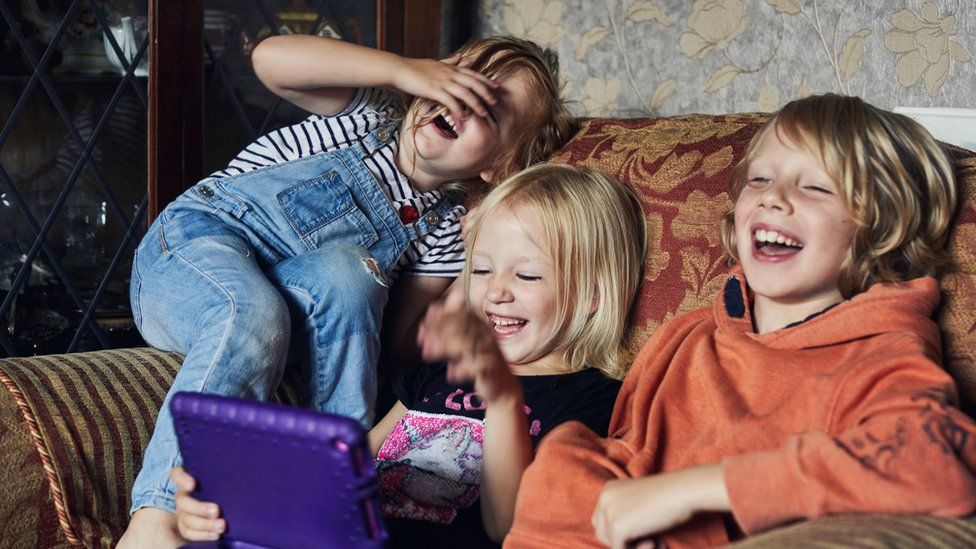 Children laughing on a sofa