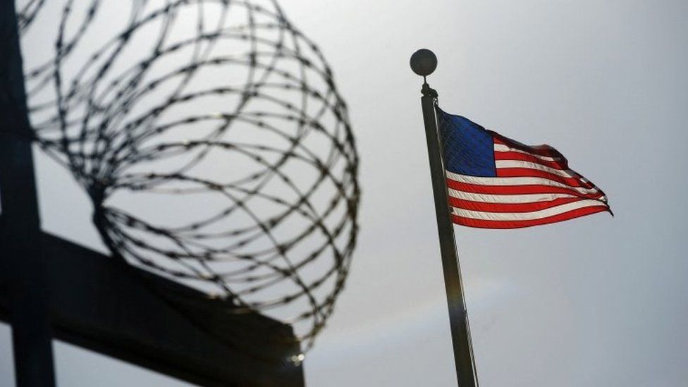 A US flag flies above a razorwire-topped fence at Guantanamo Bay. File photo