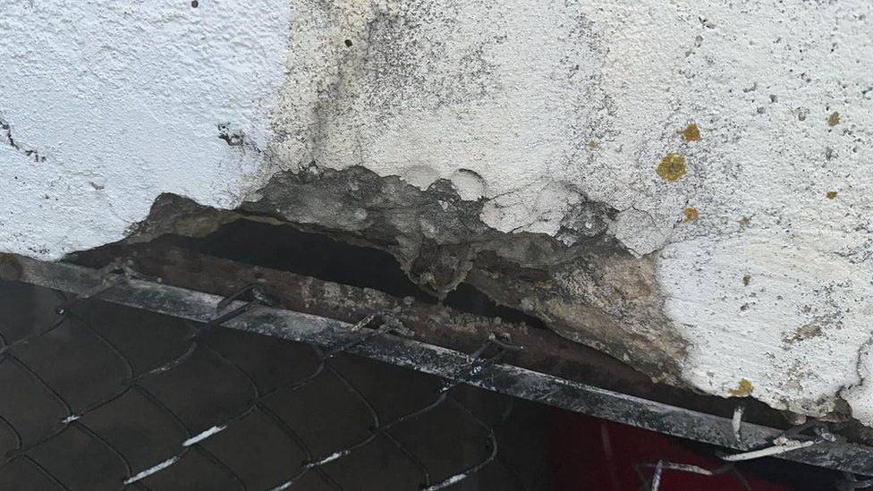 Damaged concrete over a metal fence