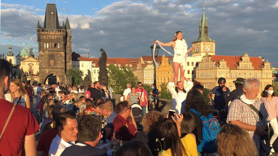 Crowds of people in Prague celebrating the 'end' of the pandemic including a street performer
