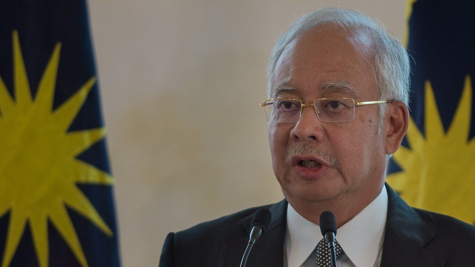 Malaysian Prime Minister Najib Razak speaks at a press conference in front of the national flag