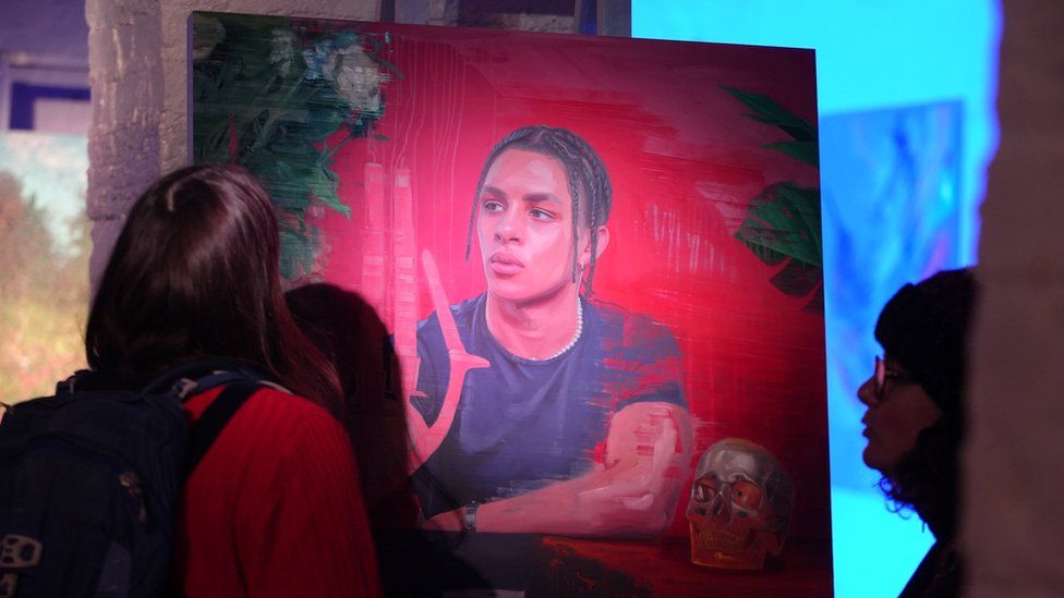 A group of people study a painting on canvas as part of Upfest Presents in a church crypt