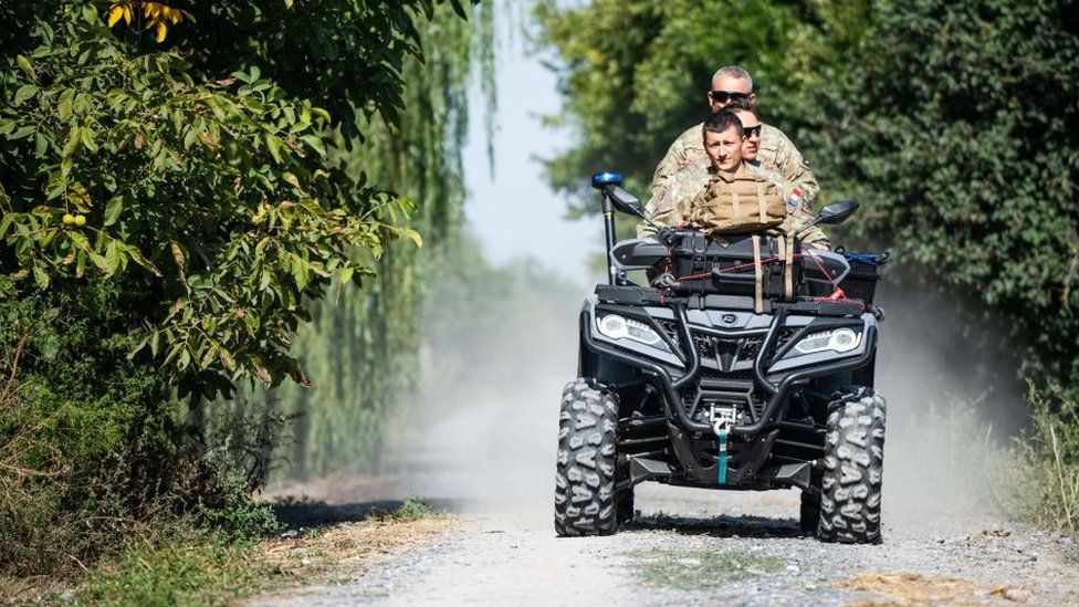 Romanian soldiers ride an ATV down a street in the village of Plauru