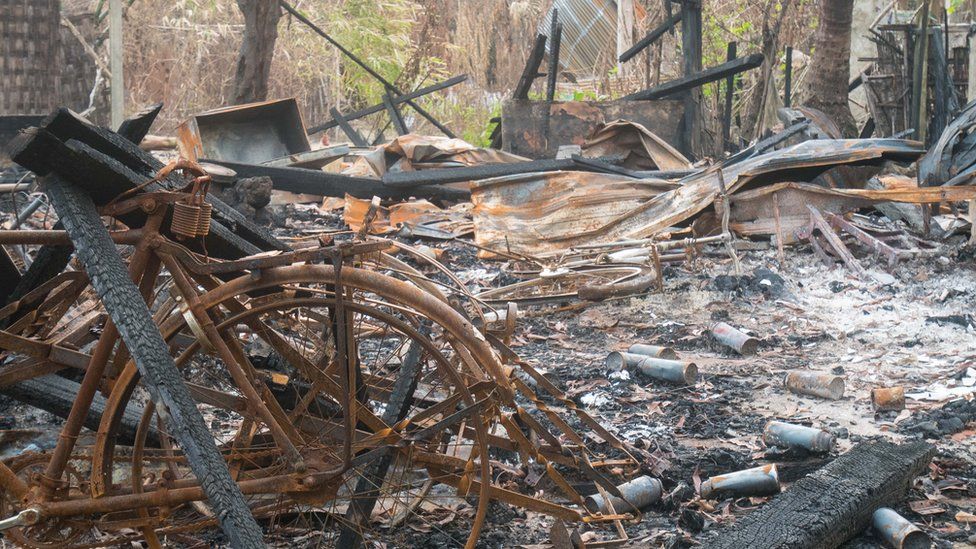 A rusted bicycle frame is seen amid the charred ruins of a Muslim village