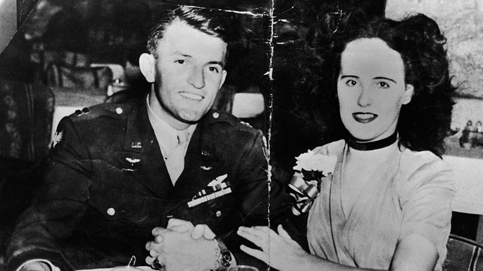 American aspiring actress and murder victim Elizabeth Short (1924 - 1947), known as the 'Black Dahlia,' sits arm-in-arm at a restaurant or bar table with American Army Major Matthew M. Gordon Jr (? - 1945), mid 1940s.
