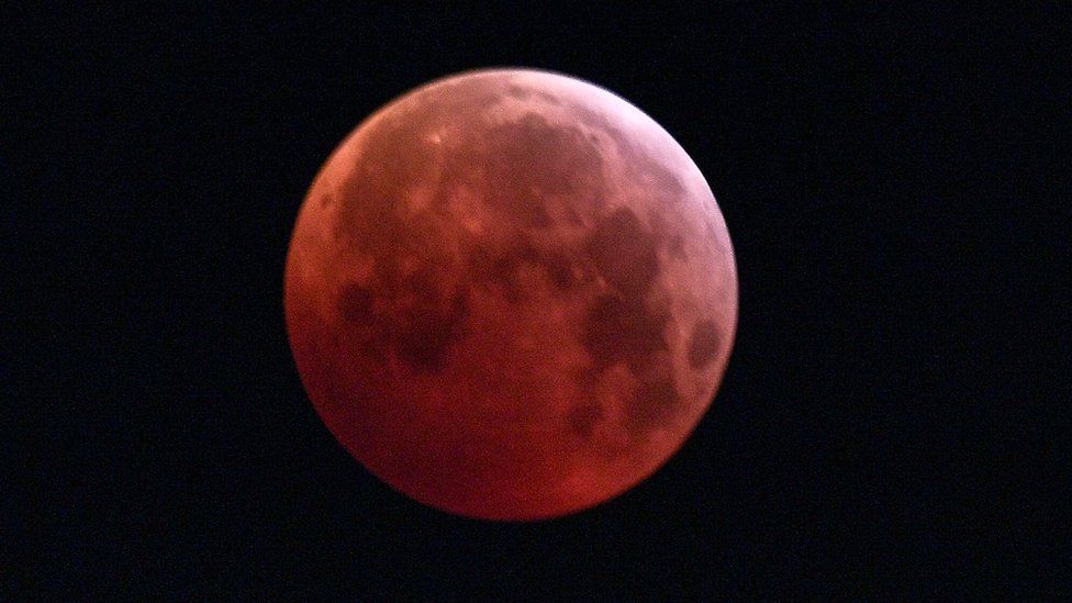 The so-called Super Blood Wolf Moon is engulfed into Earth's dark umbral shadow during a total lunar eclipse over Milan, north Italy on January 21, 2019