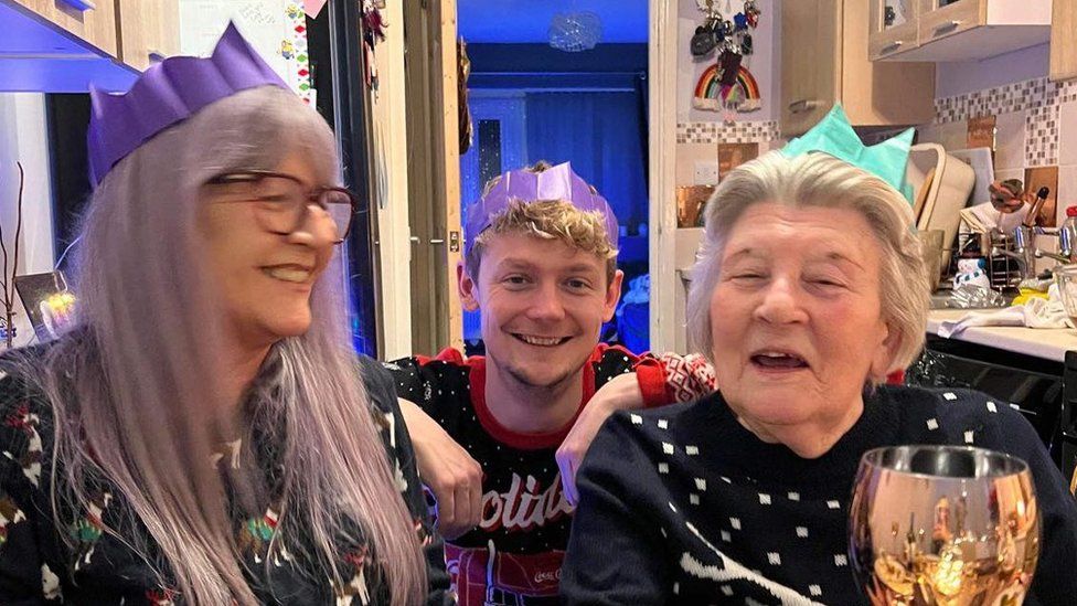 Beryl sitting with her family wearing Christmas hats