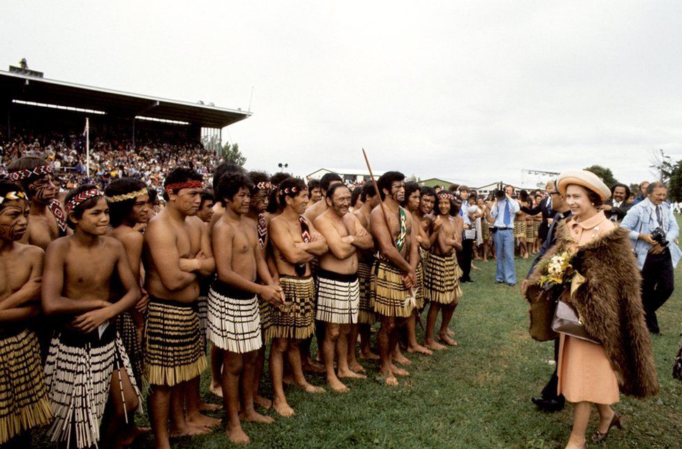 Queen Elizabeth II, wearing a cloak of brown kiwi feathers, with Maori warriors at Rugby Park, Gisborne, when she and the Duke of Edinburgh received a New Zealand Maori welcome at the opening of the Royal New Zealand Polynesian Festival.