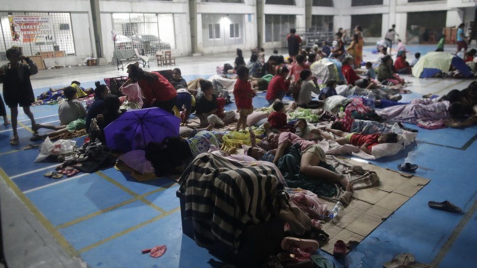 Evacuees rest inside a gymnasium turned into a temporary evacuation center in Manila, Philippines, 25 September 2022.