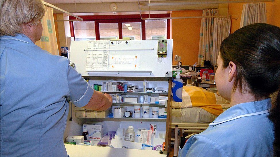 Nursing staff dispensing drugs from a trolley on a hospital warn