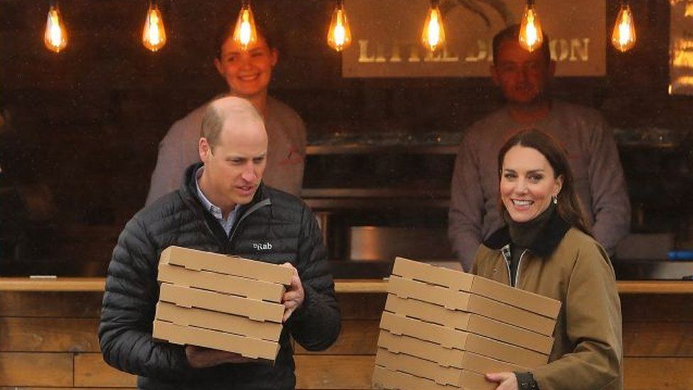 Britain's Prince William, Prince of Wales and Britain's Catherine, Princess of Wales carry take-away pizzas from a pizza van to members of the Mountain Rescue team, during a visit the Dowlais Rugby Club, in Dowlais, as part of a tour in Wales, on April 27, 2023. (Photo by Geoff Caddick / POOL / AFP) (Photo by GEOFF CADDICK/POOL/AFP via Getty Images)