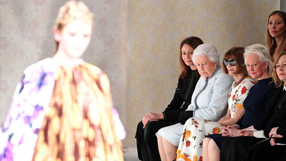 The Queen and Anna Wintour watch as a model walks the runway