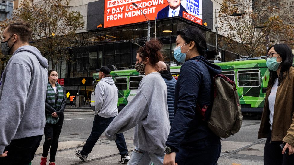 Молодые люди в масках идут по улице Мельбурна в начале мая 2021 года.